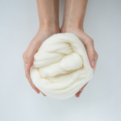 Close-up of white merino wool ball in hands.