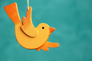 Wooden orange bird on turquoise background