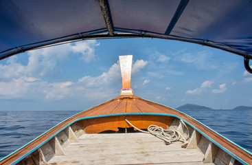 Tourist boat heading off to snorkeling diving area. Bow structure of the boat seen with curved canvas roof frame as foreground. Skin diving boat trip around Lipe island, southern Thailand.