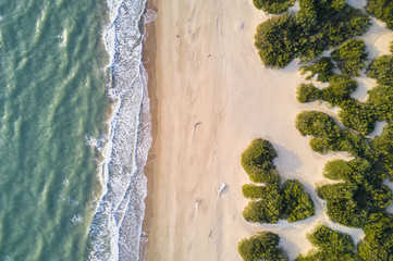 View from above, stunning aerial view of a beautiful and uncontaminated wild beach bathed by a rough sea during the sunset. - obrazy, fototapety, plakaty