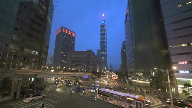 Xinyi Business District as traffic passes through a busy intersection at dusk