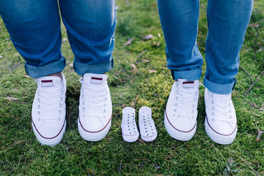 Nachwuchs erwartet - Babyschuhe neben Schuhe der Eltern