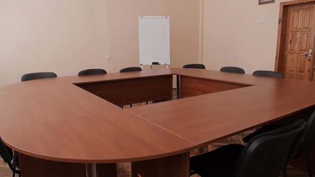 Meeting room with wooden conference-table, whiteboard and black chairs in office
