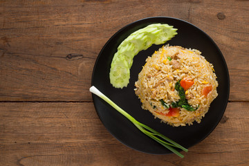 Fried rice with cucumber on black circle plate on wooden table