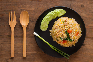 Fried rice with cucumber on black circle plate on wooden table