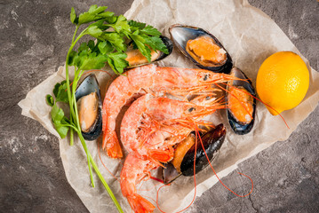 Fresh frozen prawns, for cooking on a kitchen concrete gray table. With lemon and herbs (parsley), top view