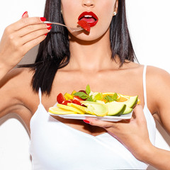 Sexy woman with red lips eating fruit salad closeup