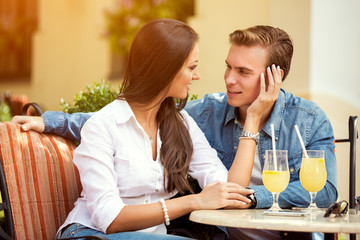 Beautiful young loving couple sitting together in cafe