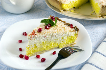 Homemade coconut cream pie in white plate with fork on light cloth napkin