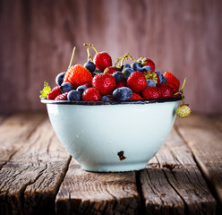 Fresh Strawberries and Blueberries  in the Iron bowl with a Cup of Milk on Vintage Wooden Background.Food or Healthy diet concept.Copy space for Text. selective focus.