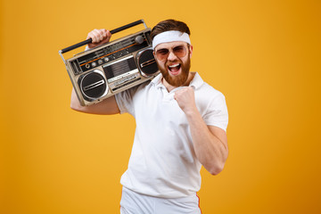 Happy young man wearing sunglasses holding tape recorder