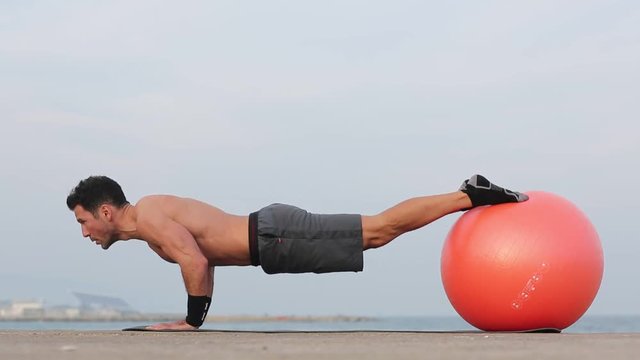 Liegestuetze mit Fitnessball am Meer windig