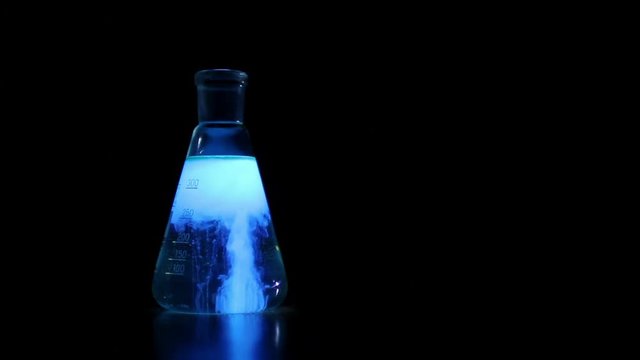 Chemical experience on black background, Fluorescent chemical reaction in the glass flask