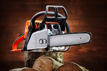 Naklejka premium Chainsaw and cut logs fire wood on brown wooden background. Renewable resource of a energy.