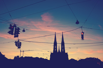 Fototapeta premium Silhouette of the Votive Church (Votivkirche) and suspended stoplights at dusk, color toning applied.