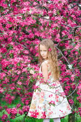 Obraz na płótnie Canvas Little girl in blooming apple tree garden enjoy spring