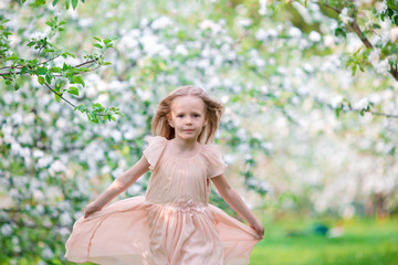 Fototapeta na wymiar Cute girl in blooming apple tree garden enjoy the warm day