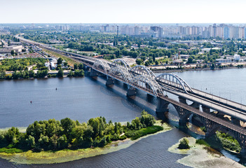 Fototapeta na wymiar Aerial view of the Kiev (Kyiv) city, Ukraine. Dnieper river with bridges. Darnitskiy bridge. Poznyaki district in the background