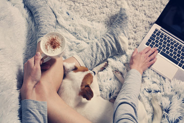 Woman in cozy home wear relaxing at home, using laptop. Soft, comfy lifestyle.