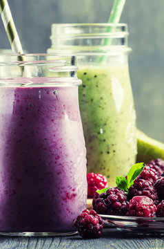 Berry smoothies in bottles, gray background, selective focus
