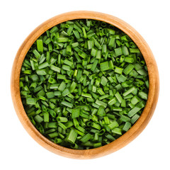 Chopped chives in wooden bowl. Fresh green edible herb of Allium schoenoprasum, used as an...