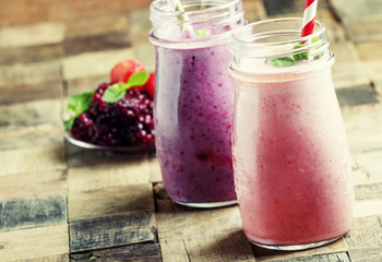 Smoothies from blackberries and strawberries in glass bottle, vintage wooden background, selective focus