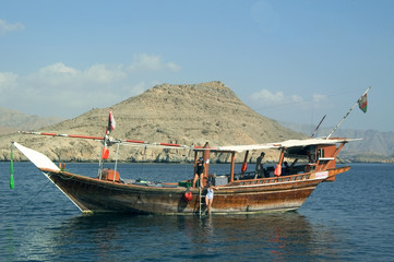 Musandam Peninsula, OMAN: A diving dhow sails the Hormuz Strait, off the Musandam Peninsula - obrazy, fototapety, plakaty