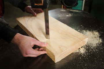 A carpenter cuts a piece of wood to the machine