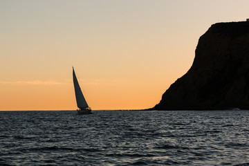 Point Loma peninsula with a nearby sailboat at dusk in San Diego, California.  