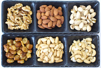 Assorted mixed nuts in black plate on white background
