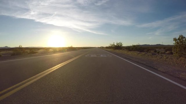 Route 66 pavement sign sunset driving shot in the California Mojave Desert.
