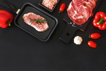 Stir fry and bbq ingredients. Thinly cut beef and raw pork steak, bell pepper, tomato, garlic, Himalayan salt over black background. Copy space, top view.