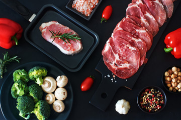 Bbq and stir fry ingredients. Thinly sliced raw meat and juicy raw steak in a pan. Fresh vegetables (bell pepper, broccoli, tomato), mushroom and spices over black board. Top view.