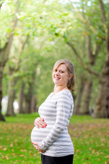 Happy and young pregnant woman in park in summer