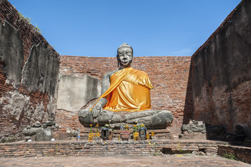 Naklejka premium Large stone Buddha statue at the partially restored ruin of Wat Worachet Tharam in the ancient city of Ayutthaya, Thailand