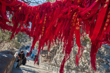 Fototapeta na wymiar Red ribbons attached to an overhanging branch on the route up Tai Shan, China