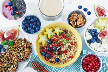 Top view of healthy breakfast with muesli, cottage cheese, yoghurt, wholegrain cookie, fresh berry and fruit, coffee on a white table. 