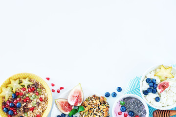 Variety of delicious breakfast dishes with fresh fruits and berries on a white table with a place for text. Muesli, cottage cheese, yoghurt, cookies and coffee. 