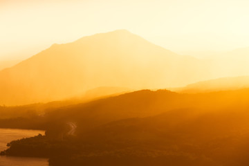 A Winding Highway Road Disappears into Mountain Layers and a Golden Sunset