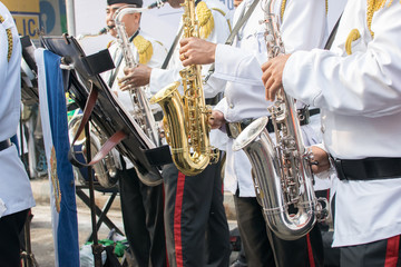 Men, dressed in white and black suits, are playing band