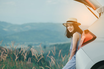 Naklejka premium Woman traveler sitting on hatchback car with mountain background in vintage tone