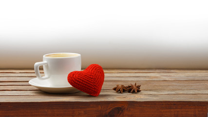 Cup of coffee, red homemade heart and stars anise on wooden table