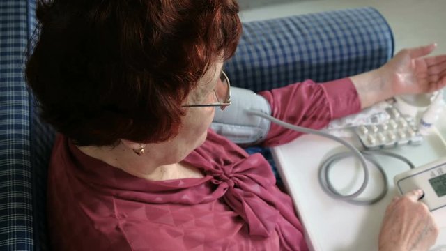 Mature lady examining her health state with manometer