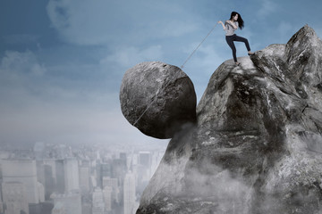 Businesswoman with big rock on the cliff