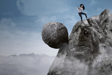 Businesswoman with big rock on the mountain