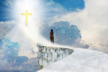 Crucifix or cross on heaven cloudy sky with lens flare and backside or rare view of women or girl...