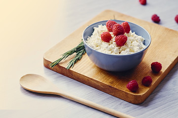 Diet curd with raspberry in a cup on a table.