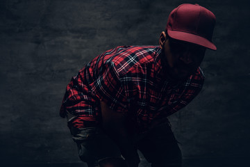 A man dressed in a red fleece shirt and a cap in a shadow. - obrazy, fototapety, plakaty