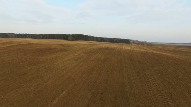 4K. Low flight and takeoff above freshly cultivated fields in spring, aerial panoramic view.
