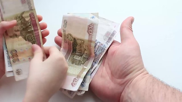 Руки ребенка перекладывают деньги в руки мужчины